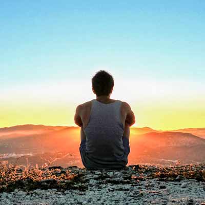 a man sitting in mountain enjoying a sunset view