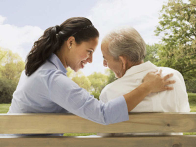 A young lady and an old man sitting on the park bench