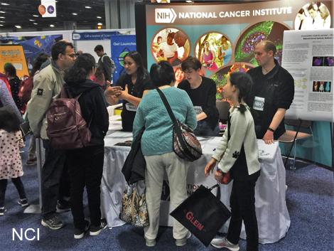 Group of people gathered around a National Cancer Institute booth