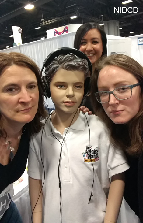 Three women with a child mannequin with headphones