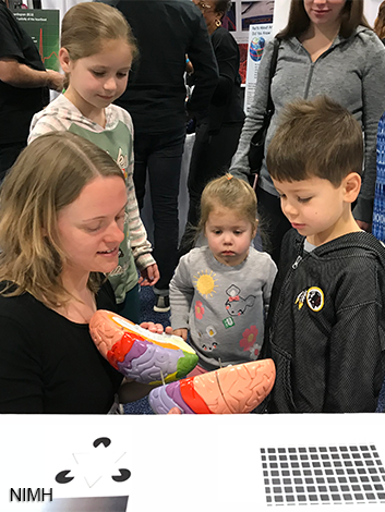 Woman holding plastic brain model while children look on